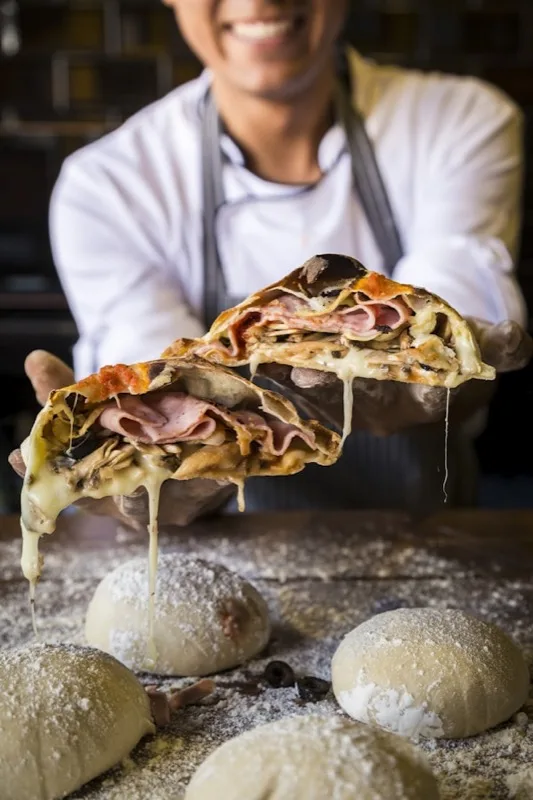 Le Chausson Calzone - Base tomate, Mozza, Emmental, Jambon, Champignons, Pointe de Crème Fraîche, Oeuf, Olives, Origan