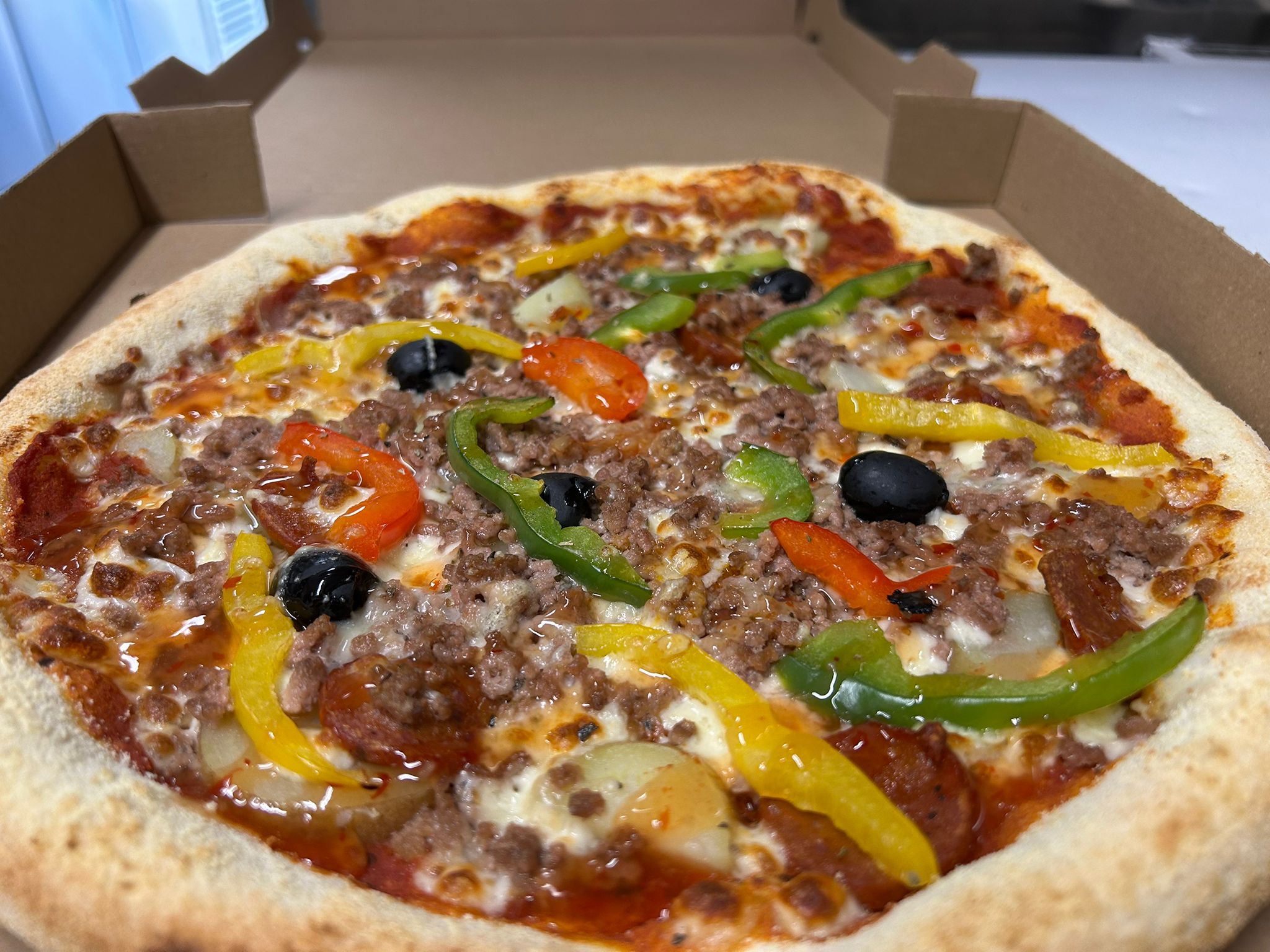 Pizza Hot - Base tomate, Mozza, Emmental, Pommes de terre, Chorizo, Viande Hachée, Poivrons, Sauce Thaï, Olives, Origan